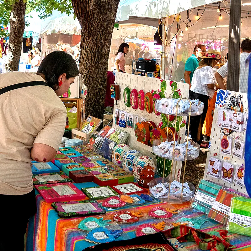 Woman shopping for artwork at the Muerto Mercado during Muertos Fest