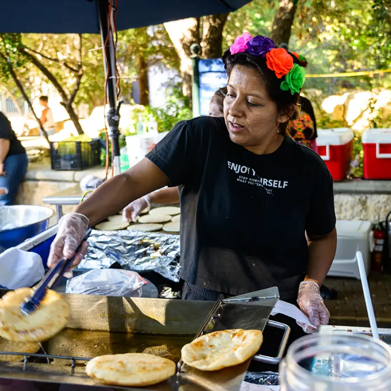 Woman wearing a flower crown preparing fresh gorditas for visitors at Muertos Fest