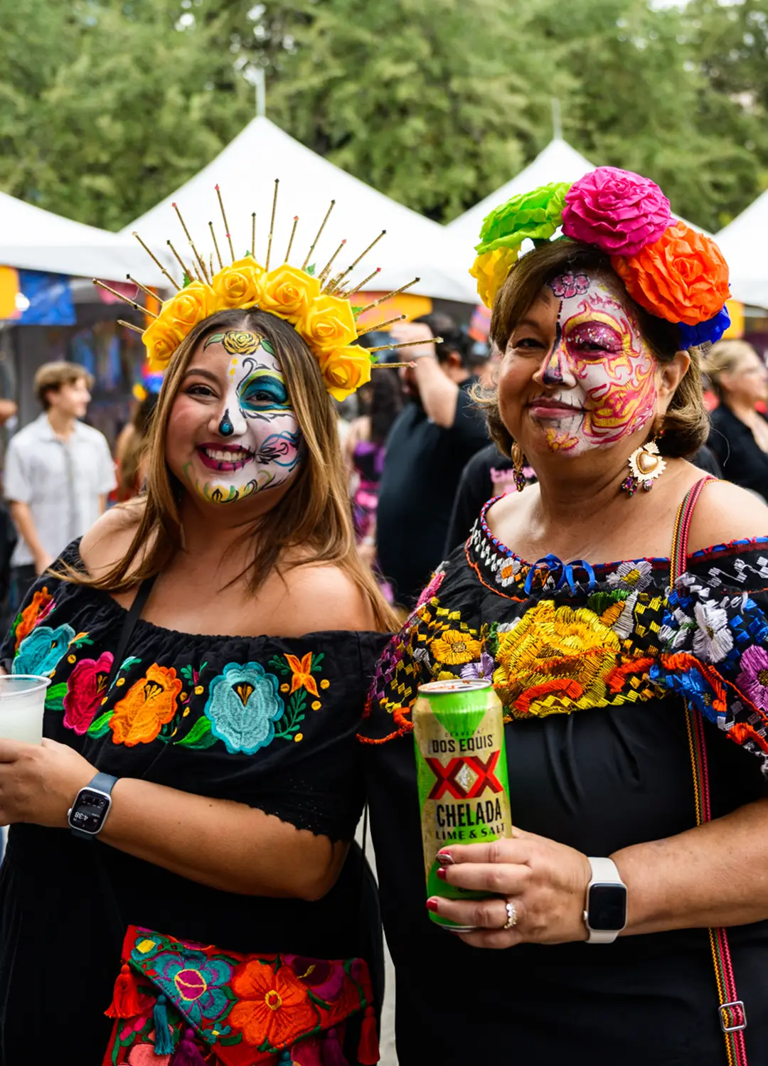 Muertos Fest attendees wearing colorful flower crowns and face paint celebrating Día de los Muertos together