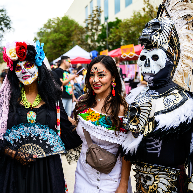 Muertos Fest attendees in colorful Día de los Muertos attire and elaborate calavera makeup