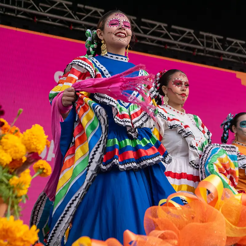Ballet Folklórico dancers performing in colorful traditional dress on stage at Muertos Fest